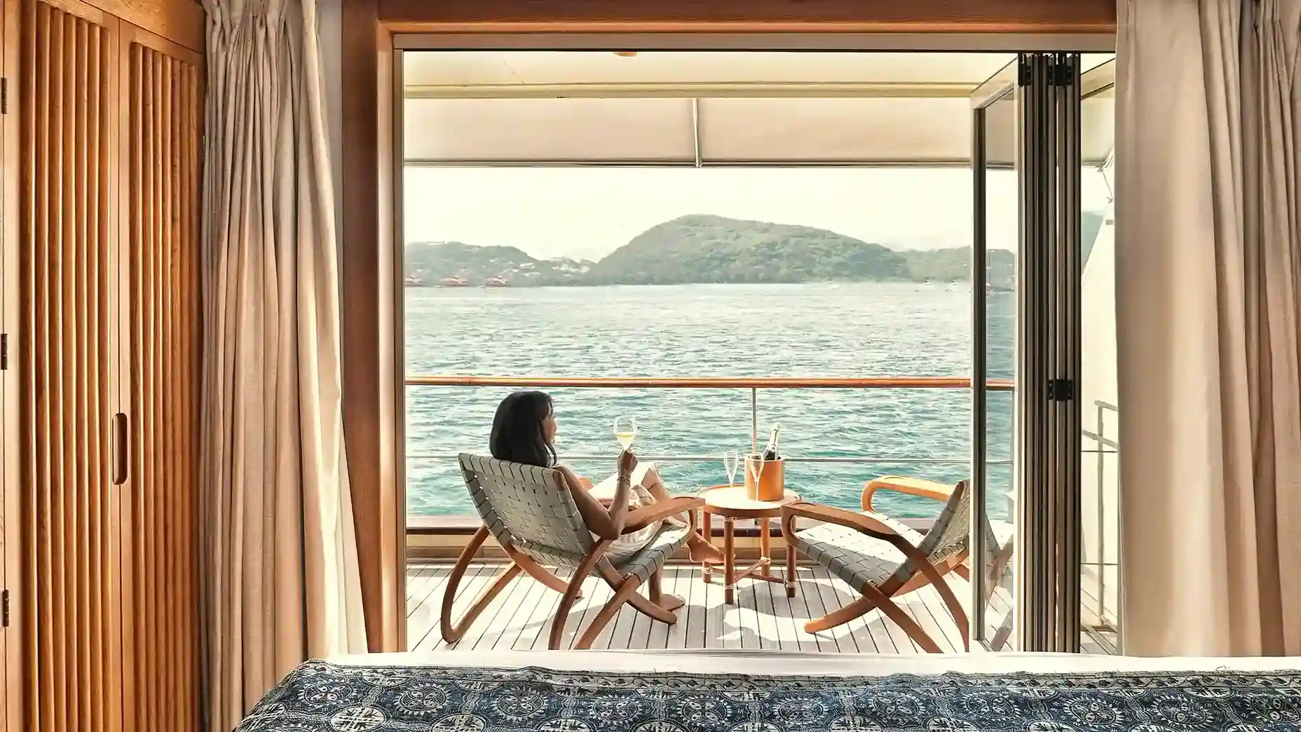 A private cabin aboard a Komodo liveaboard, opening onto a balcony over the water